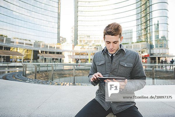 Portrait of young businessman commuter using digital tablet.