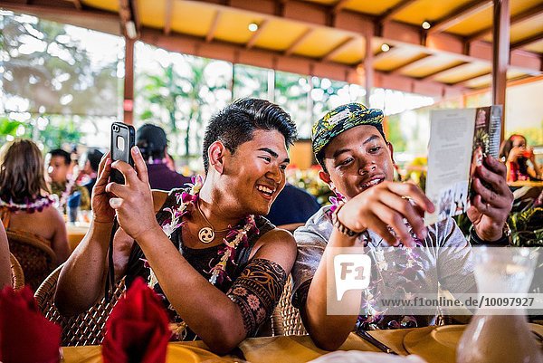Two young men reading menu in Polynesian Cultural Centre  Hawaii  USA