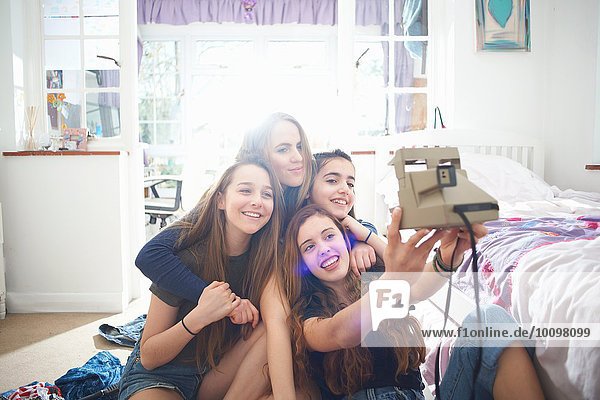 Vier Teenager-Mädchen  die sich im Schlafzimmer selbst fotografieren lassen