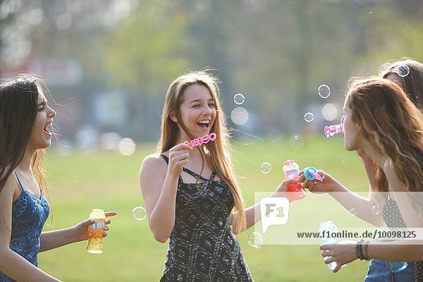 Vier Teenager-Mädchen blasen Blasen im Park