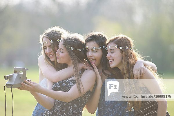 Vier Teenager-Mädchen im Park mit Sofortbildkamera Selfie
