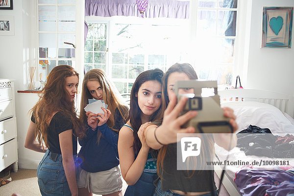 Vier Teenager-Mädchen im Schlafzimmer nehmen Instant Kamera Selfie