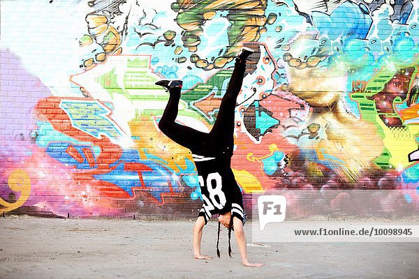 Junge Frauen im Handstand Breakdance Freeze gegen Graffiti