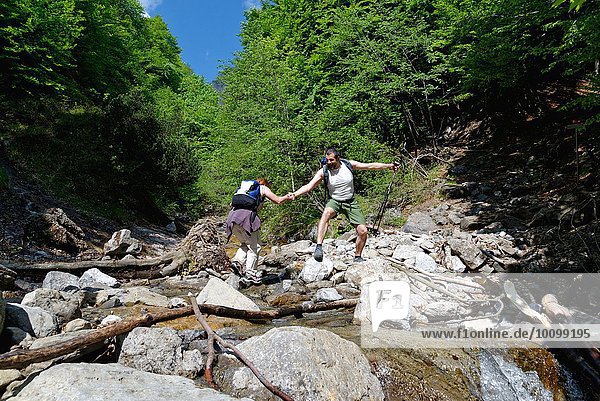 Two mature hikers crossing river
