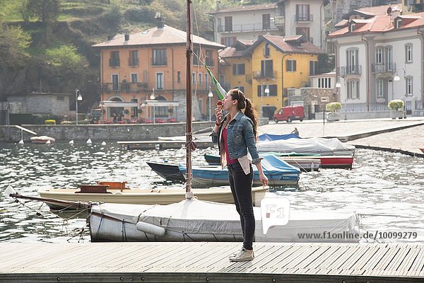 Junge Frau steht am Pier und isst Eis am Mergozzo-See  Verbania  Piemonte  Italien