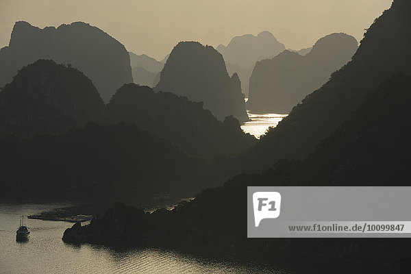 Boat on the water at sunset in the Ha Long Bay or Vinh Ha Long  limestone cliffs  UNESCO World Heritage Site  Gulf of Tonkin  North Vietnam  Vietnam  Asia
