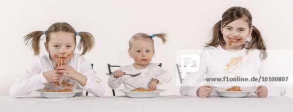 Three girls eating spaghetti at table