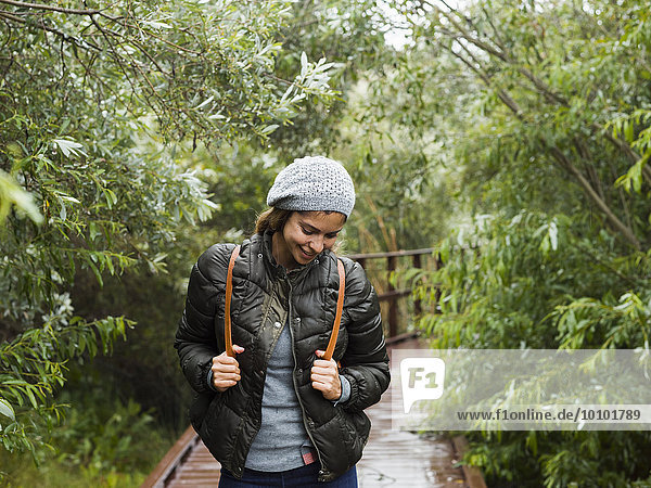 A young woman with beret and rucksack walking on a path.