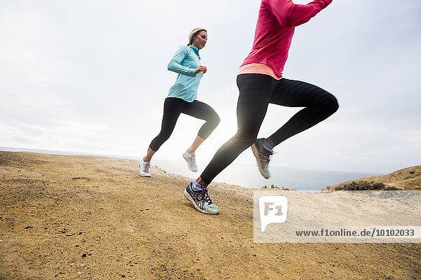 Two women jogging along the coast.