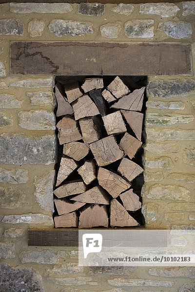 Brennholz in einer Nische in einer Steinmauer gestapelt.