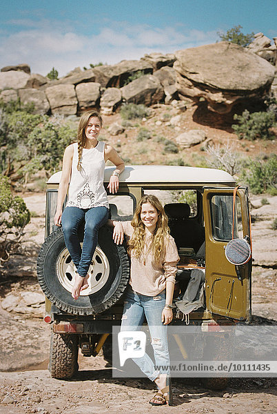Two women standing by a 4x4 on a mountain road.
