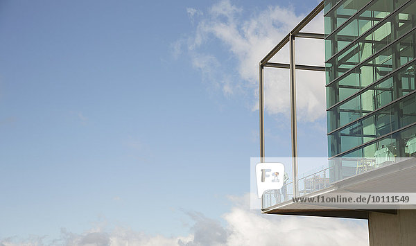 Männer  die auf einem Balkon aus Glas stehen  stoßen gegen den blauen Himmel.