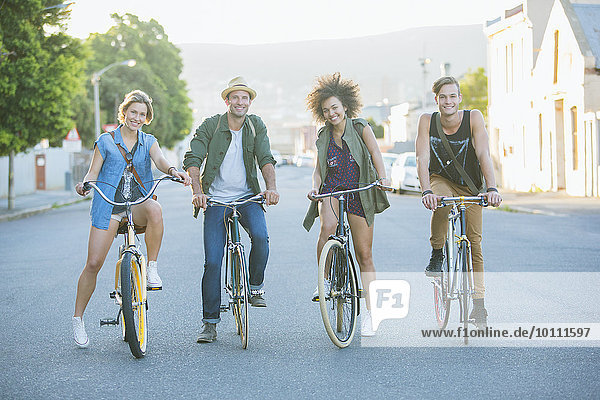Portrait lächelnde Freunde sitzen auf Fahrrädern auf der Straße