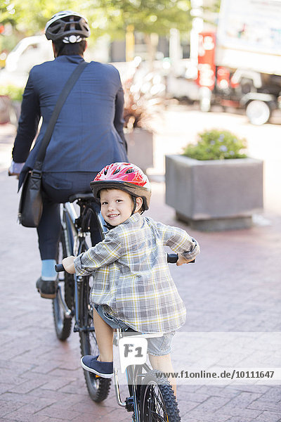Portrait smiling boy riding tandem bicycle with businessman father