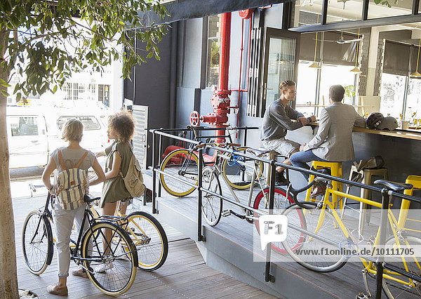 Menschen mit Fahrrädern im städtischen Außencafé