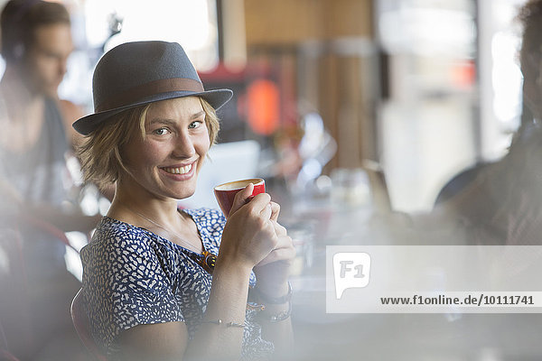 Portrait smiling woman in hat drinking espresso in cafe