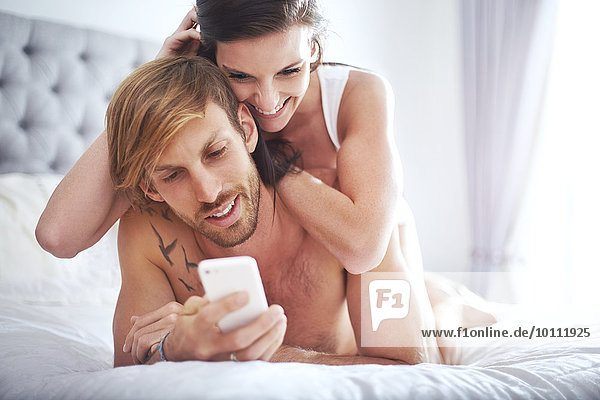 Paarverlegung auf dem Bett SMS mit Handy