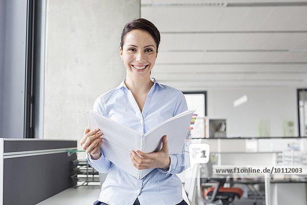 Portrait smiling businesswoman holding report in office