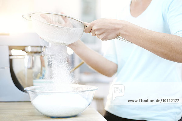 Woman sifting flour and baking in kitchen