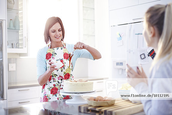 Woman frosting cake baking in kitchen