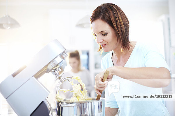Woman baking with stand mixer in kitchen