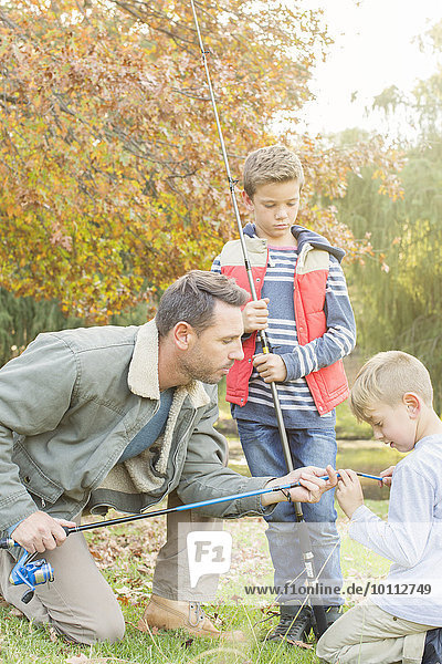 Father teaching sons to prepare fishing rods