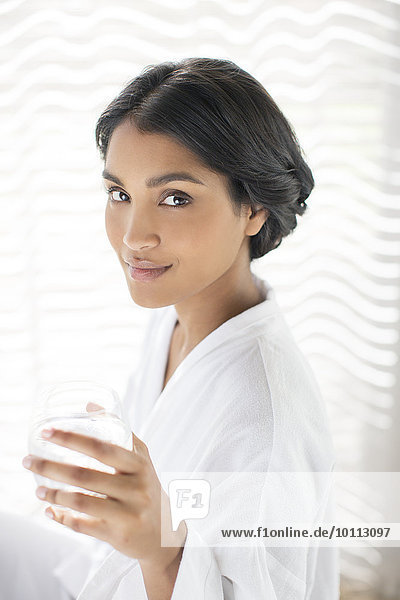 Portrait confident woman in bathrobe drinking water
