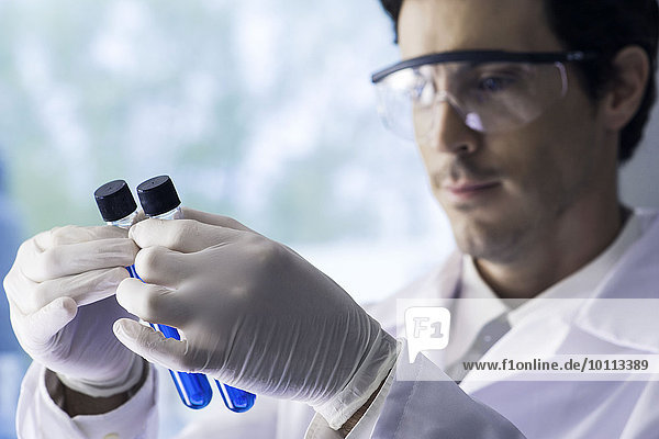 Wissenschaftler untersuchen Reagenzgläser mit blauer Flüssigkeit im Labor
