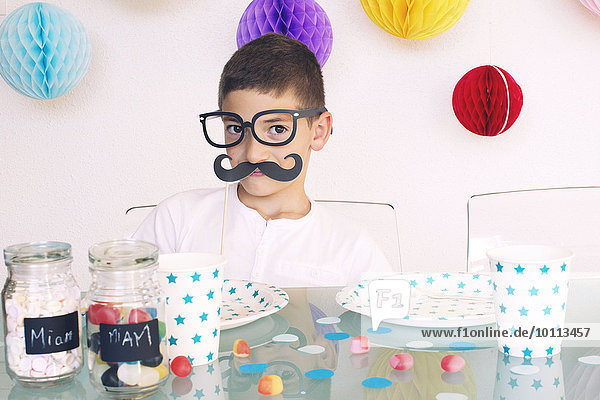 Boy wearing fake glasses and mustache at a birthday party