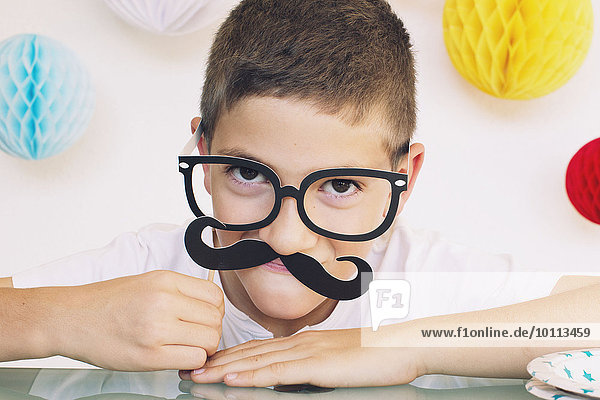 Boy wearing fake mustache and glasses at a birthday party
