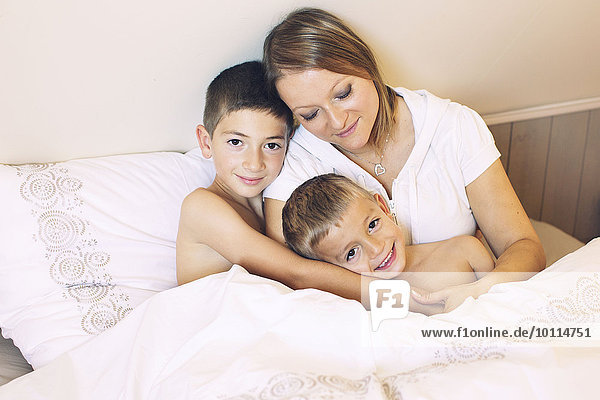 Mother and young sons together on bed  portrait