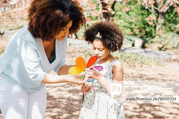 Mutter helfende Tochter mit farbenfrohem Pinwheel-Spielzeug