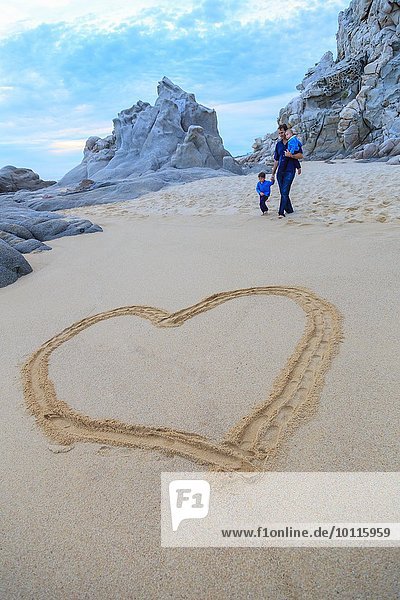 Vater und Söhne am Strand  Herzform im Vordergrund