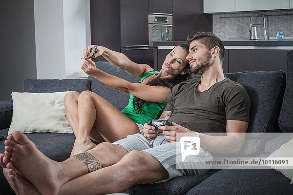 Junges Paar auf dem Sofa mit Smartphone Selfie