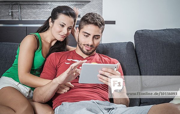 Young couple on sofa using digital tablet