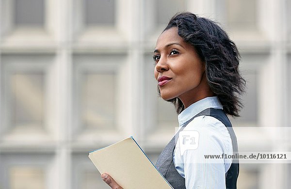Portrait of young business woman holding paper work  looking away  side view