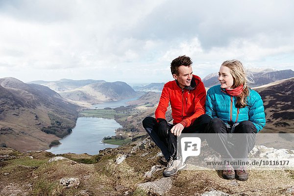 Young couple sitting on hilltop  Honister Slate Mine  Buttermere  Crummock Water  Keswick  Lake District  Cumbria  United Kingdom