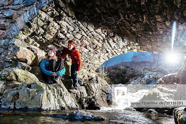 Junges Paar beim Wandern  Rasten unter der Brücke  Ashness Bridge  Keswick  Lake District  Cumbria  Vereinigtes Königreich