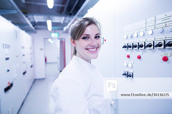 Porträt der jungen Wissenschaftlerin neben der Maschine im Technikraum