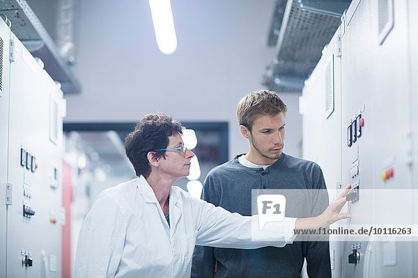 Wissenschaftler und Techniker beim Drücken des Schalters im Technikraum