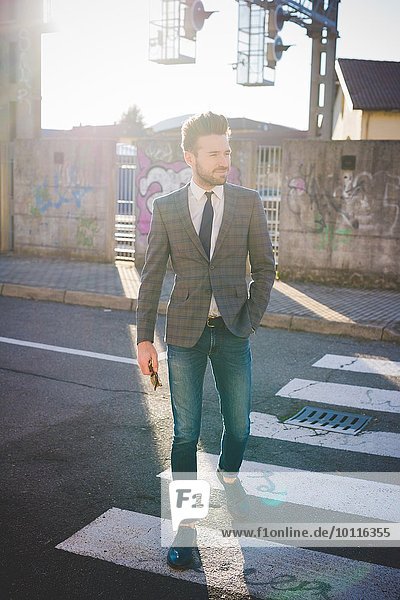 Stilvoller junger Mann auf dem Fußgängerüberweg