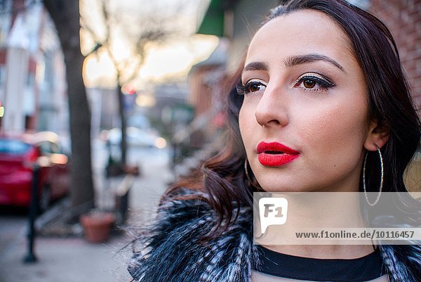 Nahaufnahme der glamourösen jungen Frau auf der Straße mit rotem Lippenstift
