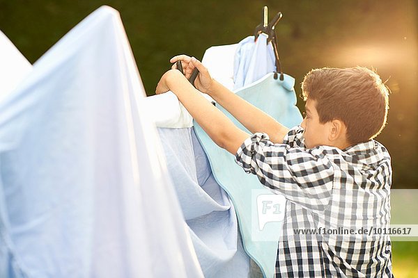 Junge legt Bettlaken auf hausgemachtes Zelt im Garten