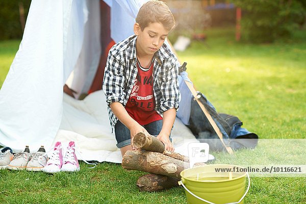 Junge bereitet Baumstämme für Lagerfeuer im Garten vor