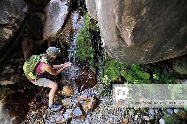 High angle view of hiker cupping hands under waterfall collecting water