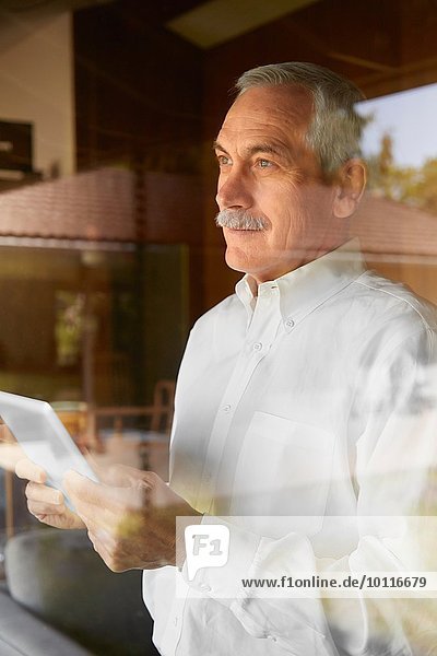 Senior Mann zu Hause  mit digitalem Tablett