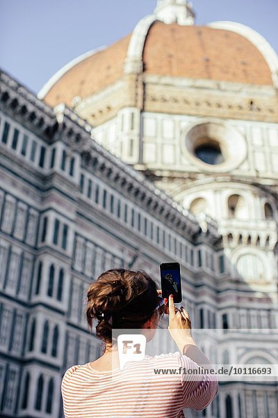 Flachwinkel-Rückansicht einer erwachsenen Frau mit Smartphone zum Fotografieren, Dom, Florenz, Italien