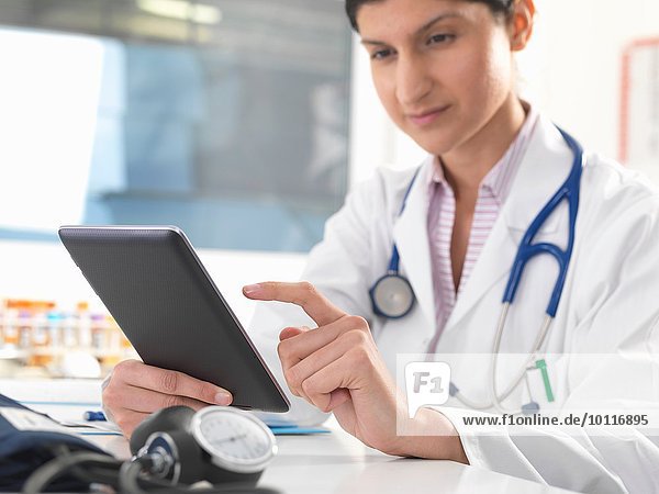 Female doctor updating medical records on digital tablet