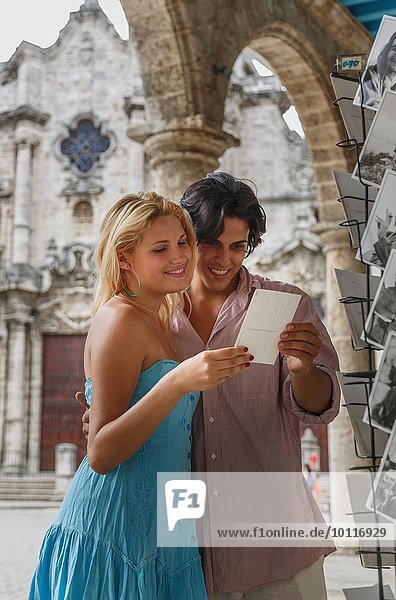 Junges Paar beim Betrachten von Postkarten auf der Plaza de la Cathedral of Havana  Kuba
