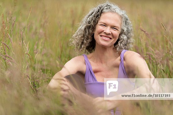 Portrait of mature woman sitting in long grass